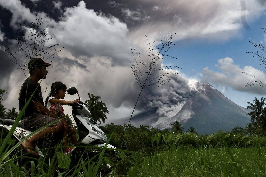 Homem e criança em moto observam a erupção do monte Merapi, na Indonésia, no qual a nuvem de cinzas atingiu 3000 m