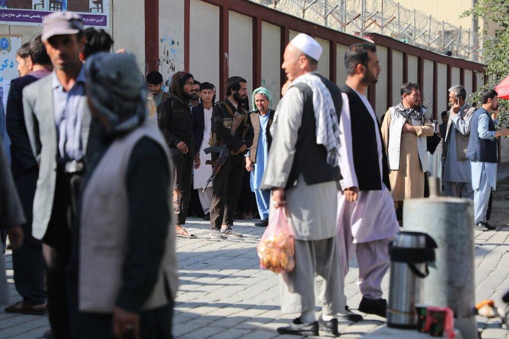 Combatentes do Talibã montam guarda enquanto as pessoas se reúnem para procurar parentes do lado de fora de um hospital em Cabul