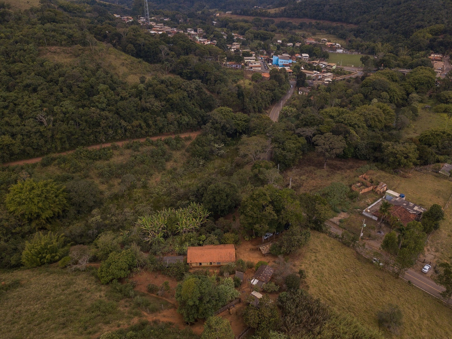 Foto aérea mostra casa dos idosos, no canto inferior, cercada de matas e, ao fundo, o distrito de Santa Quitéria