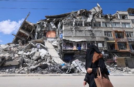 Palestina caminha diante de escombros de edifício na Cidade de Gaza